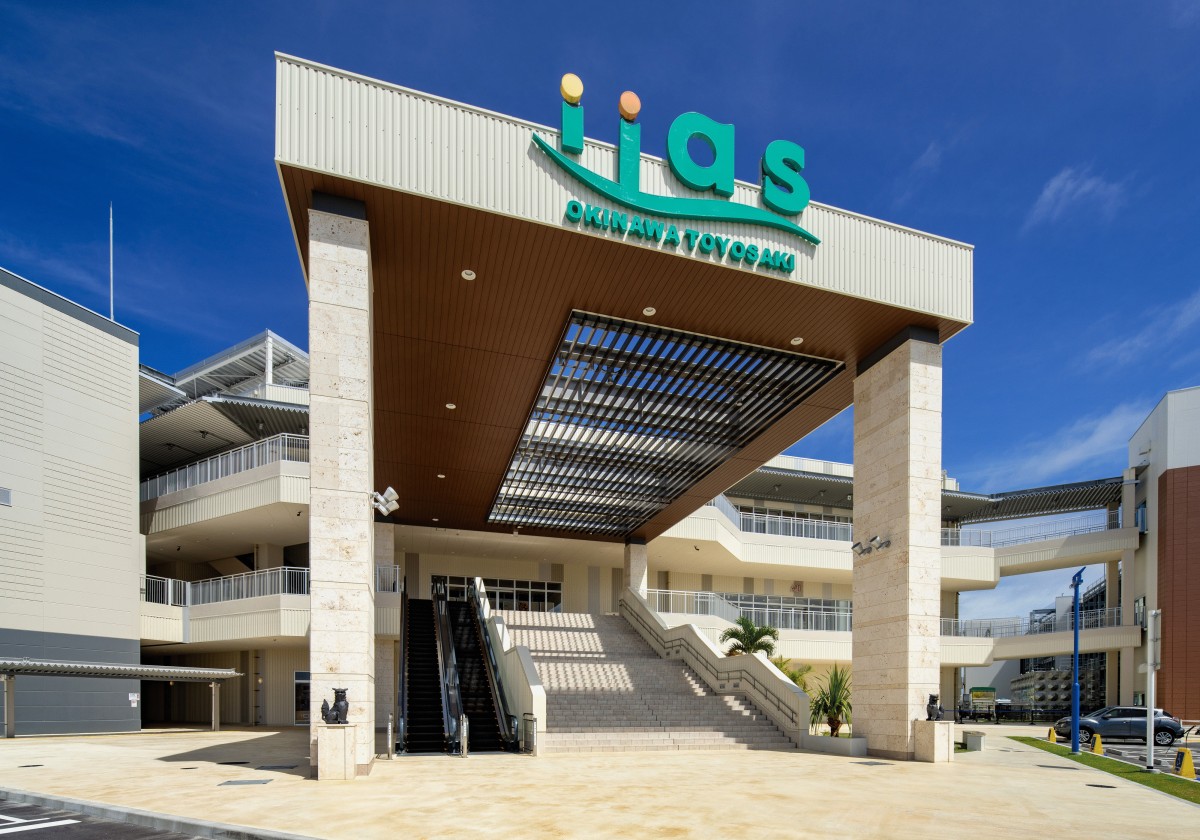 緑色のiiasの看板が掲げられた白いゲートとその中を通る建物へと続く階段の写真