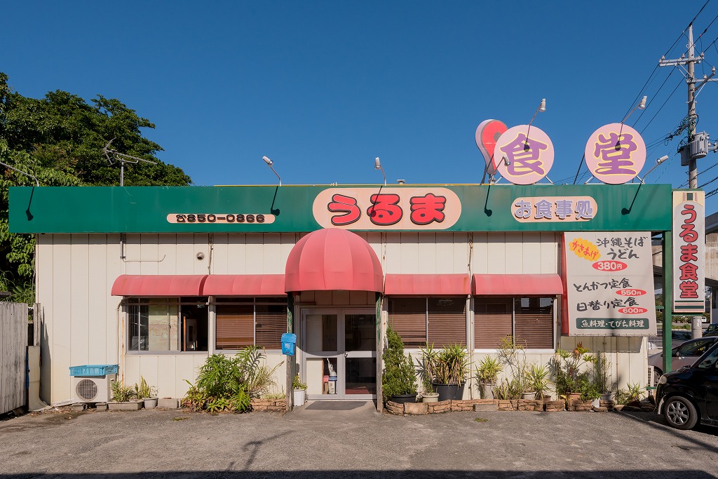 緑の屋根にうるま食堂の看板を掲げた赤いひさしある店舗の写真