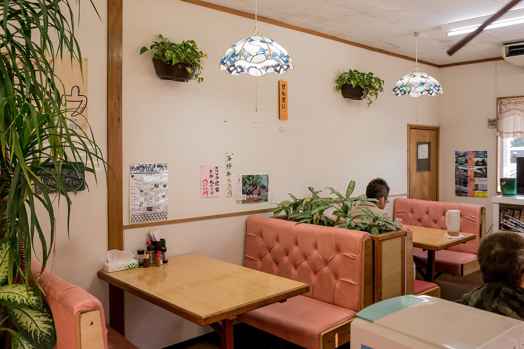 白い壁に面したテーブル席が並んだ店内の写真