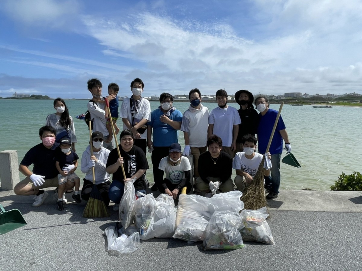 沖縄行政システム株式会社の人たちがゴミ袋を前に並んでいる写真