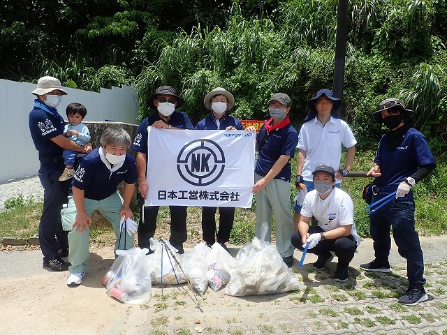 日本工営株式会社の人たちがゴミ袋を前に並んでいる写真