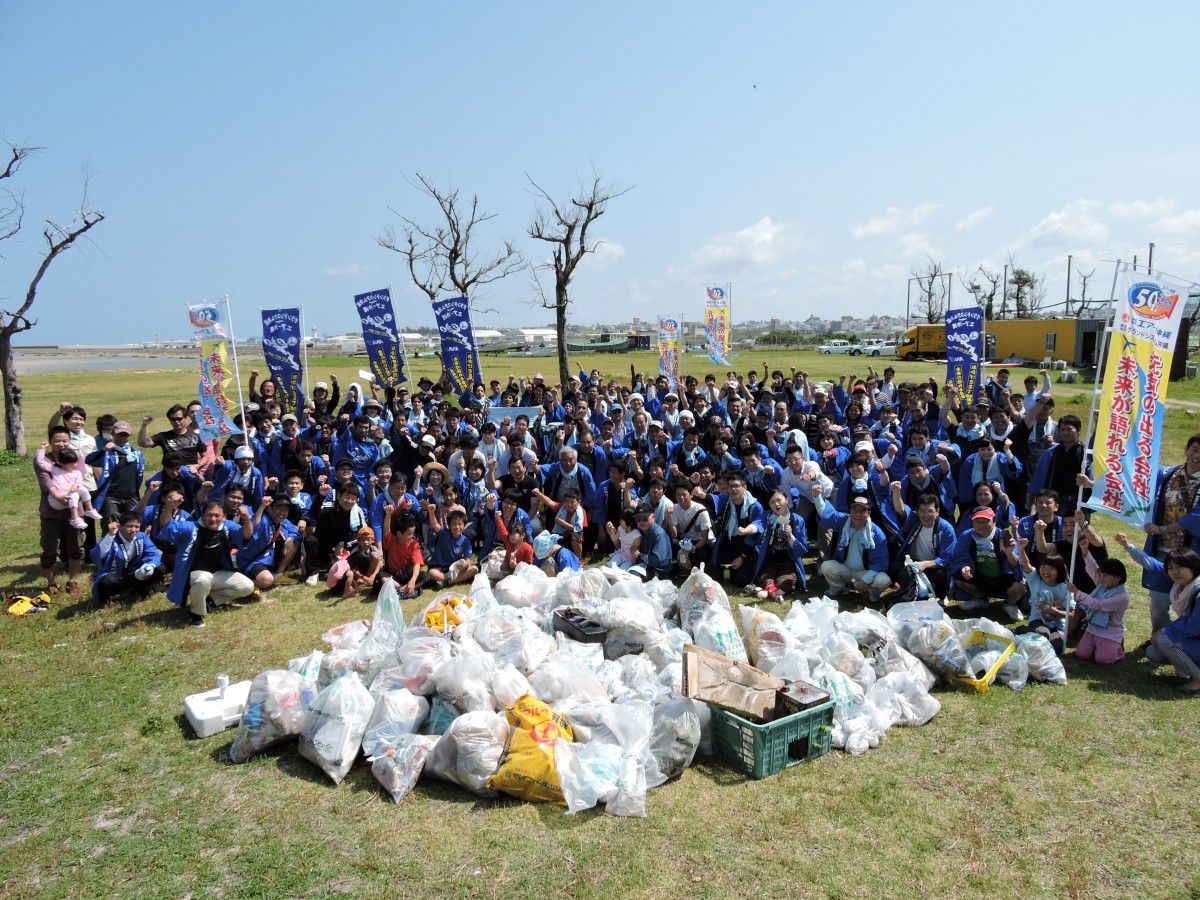 エアー沖縄グループの人たちがゴミ袋を前に並んで集合している写真