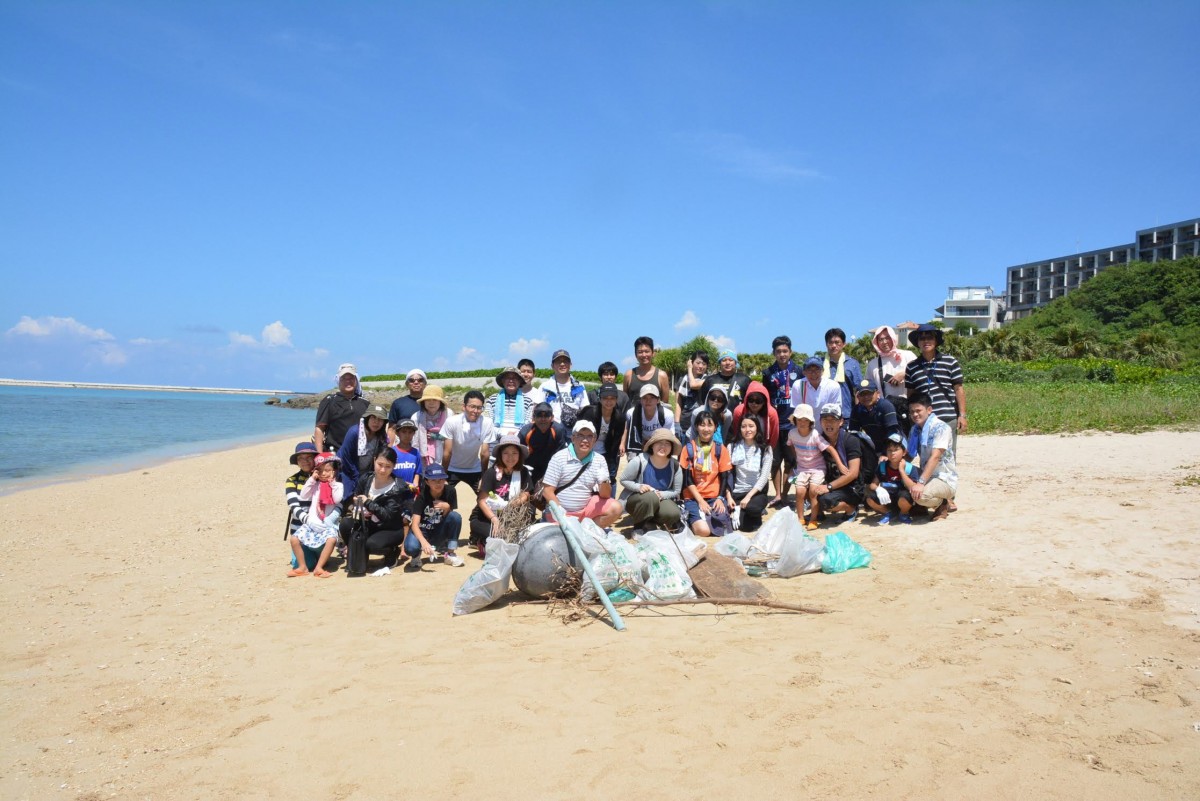 日本旅行業協会沖縄支部の人たちがゴミ袋を前に並んでいる写真