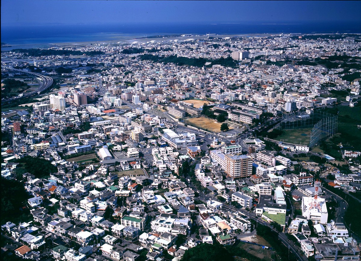 上空から撮影された、奥に海が見える市街地の景観の写真
