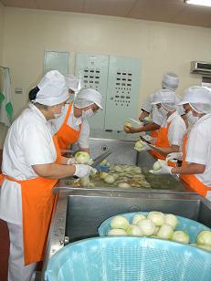 複数の給食職員が玉ねぎを包丁で切っている写真
