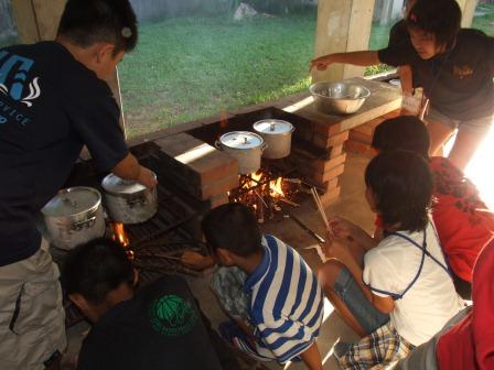 屋外の調理スペースで子供達が火をおこして料理をしている写真