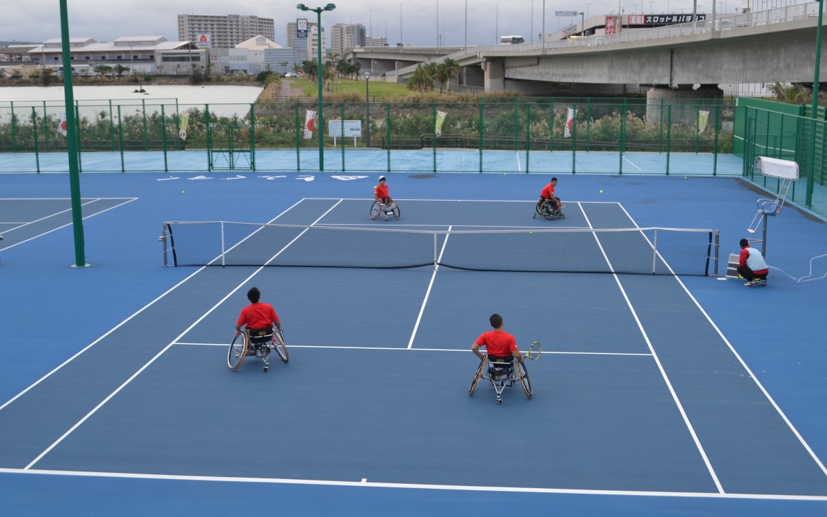 テニスコートで車いすに乗って4人の男性がテニスをしている写真