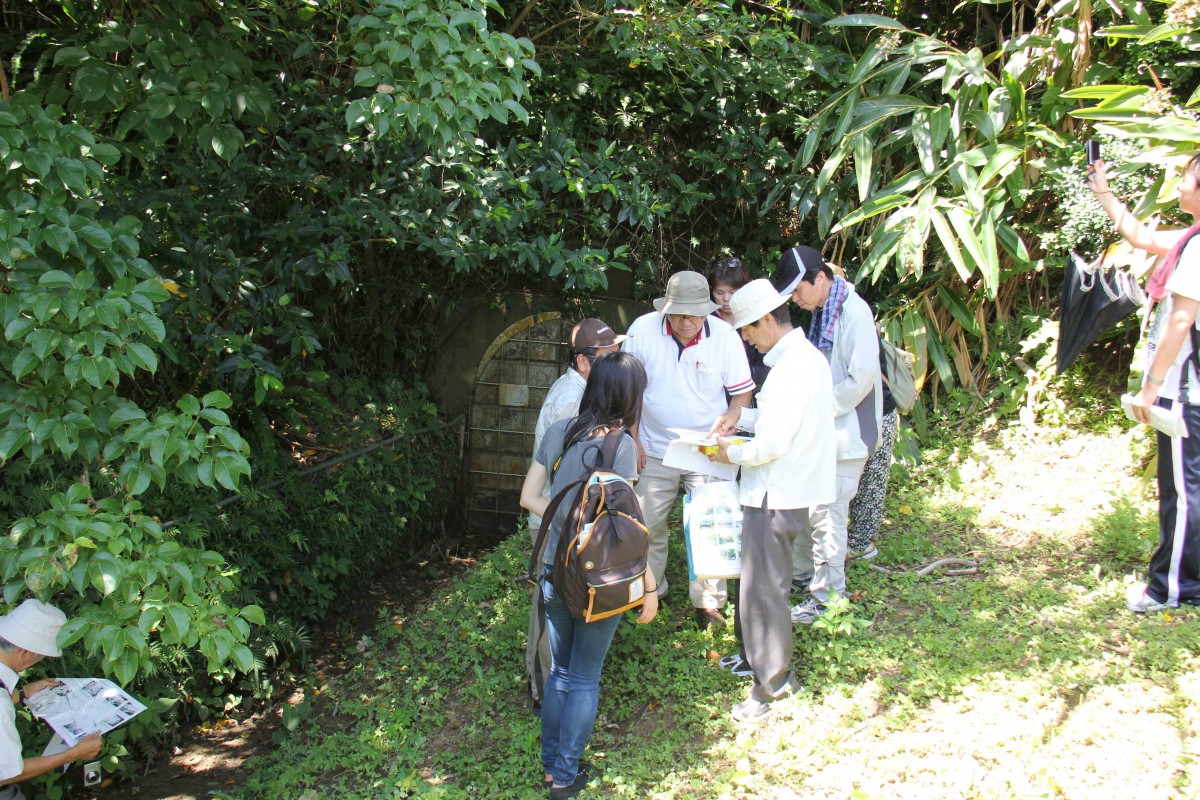 茂みのそばで、参加者たちが集まってガイドマップを見ている写真