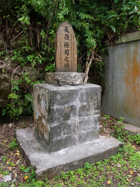 「長峰按司之碑」と書かれた石碑が、石の台座の上に置かれている写真