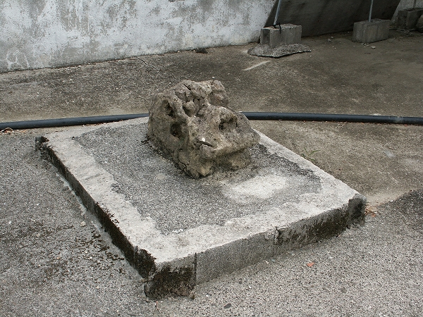 石でできた台座の上に、くずれかかったシーサーの顔部分が置かれている写真