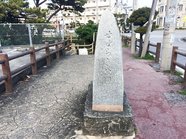 歩道の中央に、せせらぎ公園と書かれた石碑が立っている写真