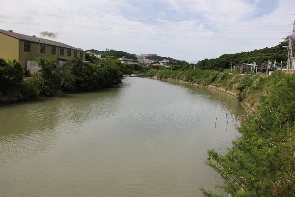 両岸が草に覆われて、画面左奥にカーブするように流れている大きな川の写真