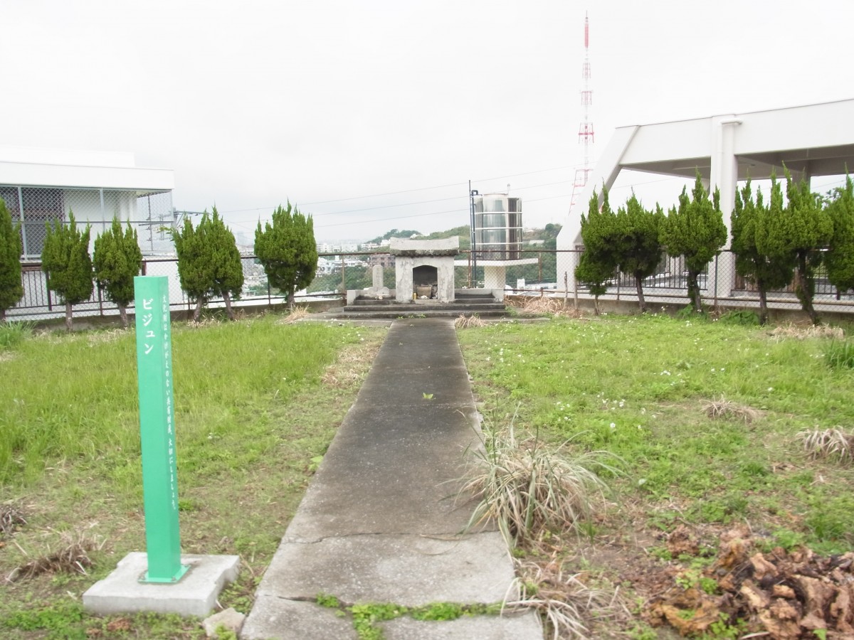 緑の芝生の中に、祠に続く石の道が敷かれている写真