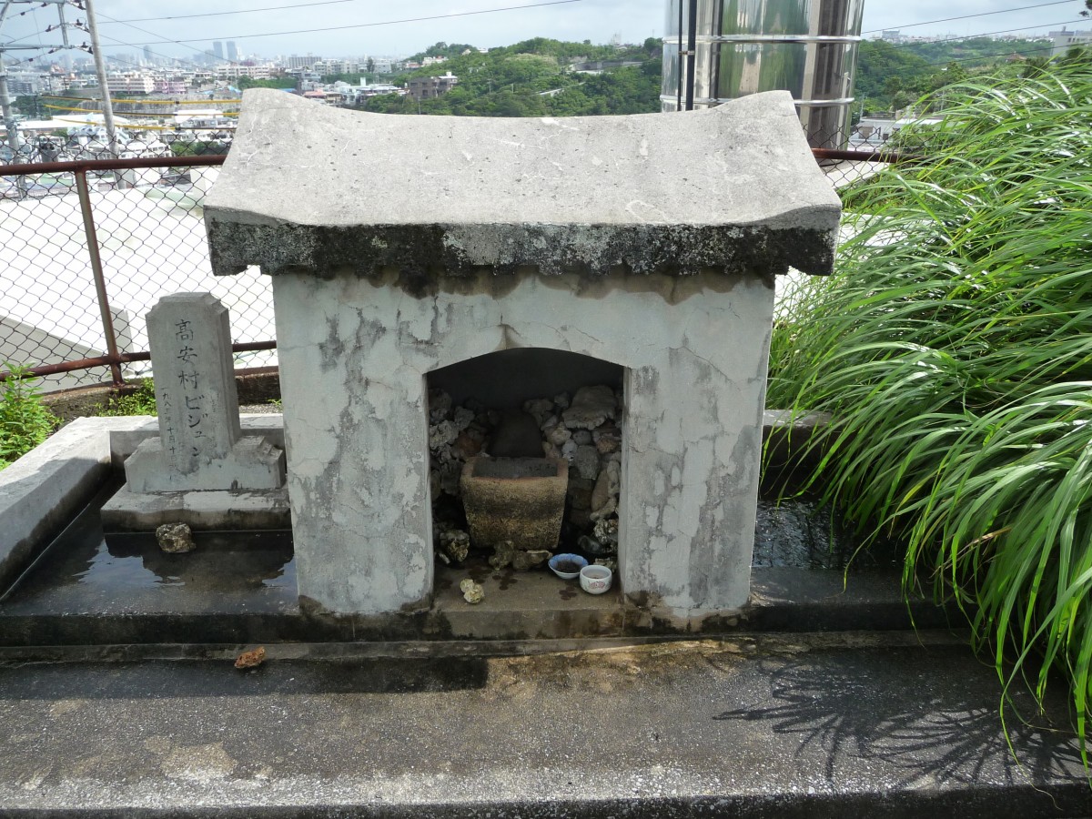 高安村ビジュンと書かれた石柱の横に、小さな石の祠が置かれている写真