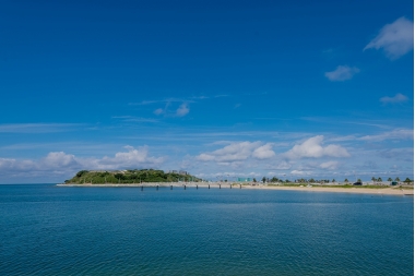 美しい海面と緑の丘と白い砂浜のある島の写真(瀬長島 とみぐすく観光ガイドへリンク)