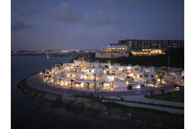 夜間で明かりの灯った、海辺に円形に建築されたテラスの写真(ウミカジテラス とみぐすく観光ガイドへリンク)