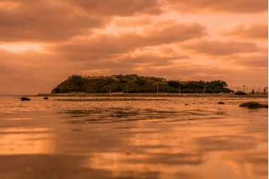 夕日で赤くなった、島と周辺の写真(瀬長島 サンセット とみぐすく観光ガイドへリンク)
