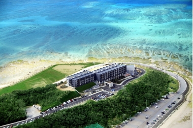 周りに碧い海と砂浜が広がり、その中央の緑の丘に建つ瀬長島ホテルの写真(瀬長島ホテル とみぐすく観光ガイドへリンク)