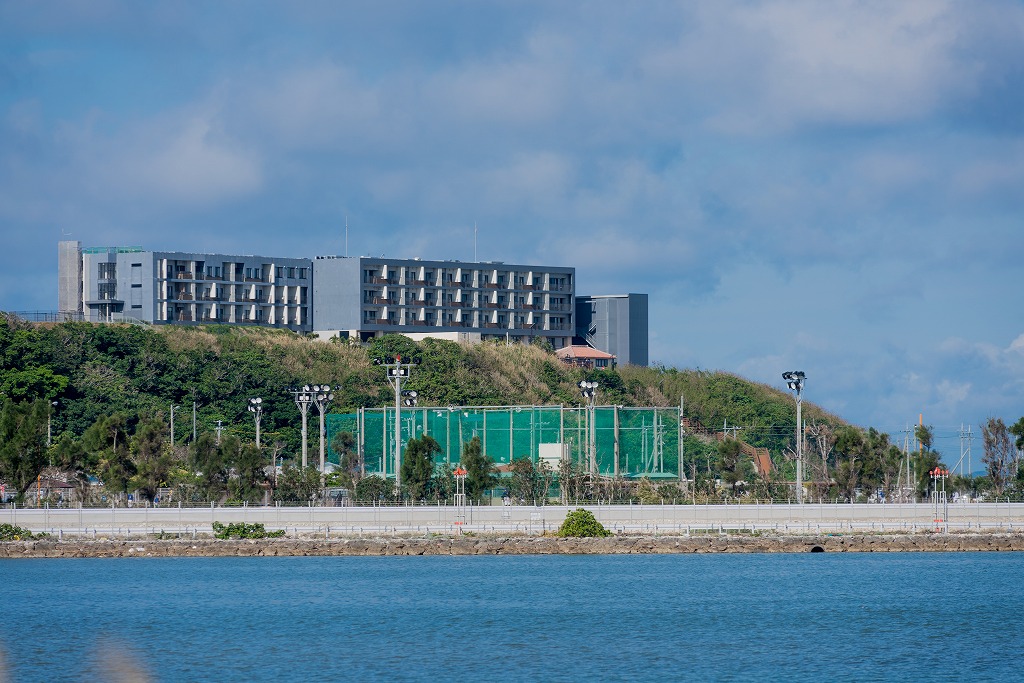 手前に海と奥の丘に建つ瀬長島ホテルの写真