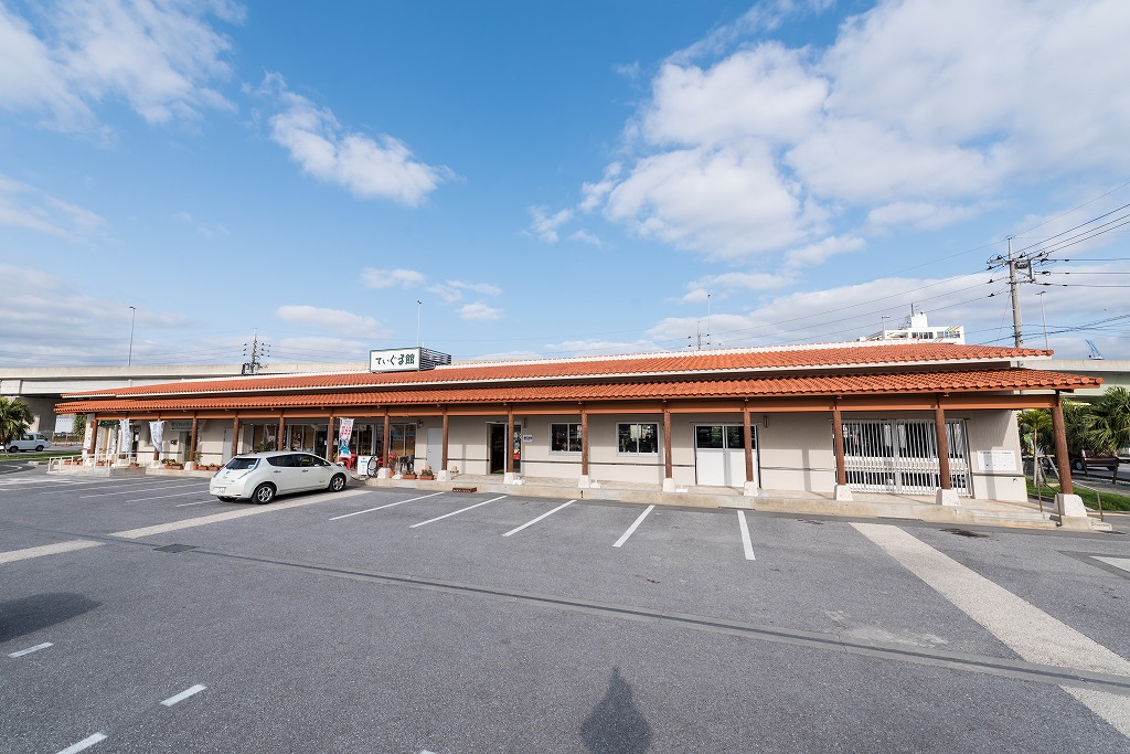 赤茶の瓦屋根の横長の建物と駐車場の写真