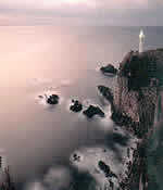 海に面した崖の上に白い灯台が建っている写真