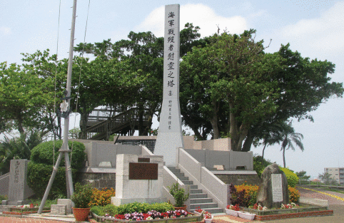 花や生け垣に囲まれている海軍戦没者慰霊之塔と書かれた縦に長い石碑の写真